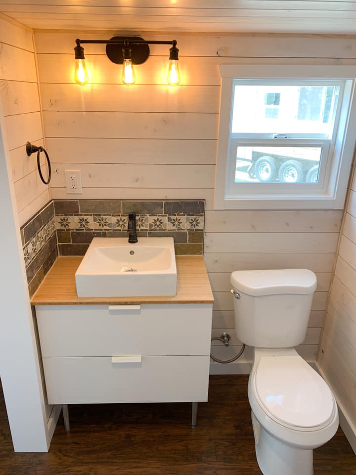 Finished tiny home bathroom with vanity, toilet and patterned backsplash