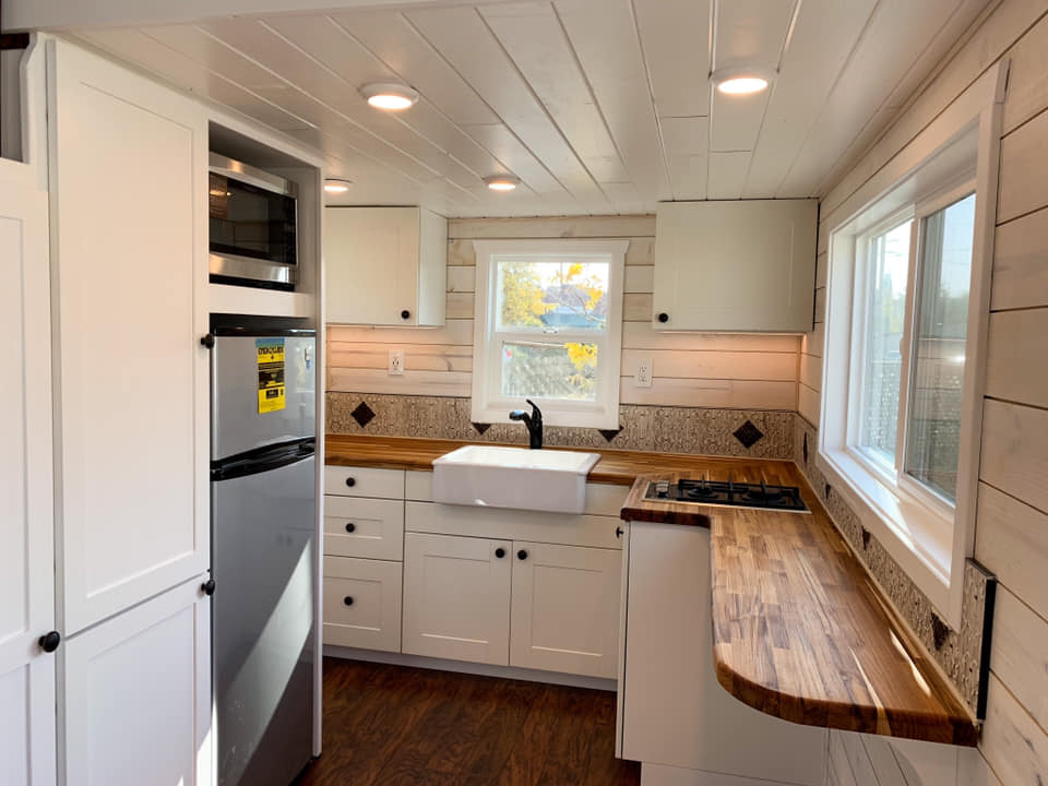 Finished tiny home kitchen with white cabinetry and wood countertops