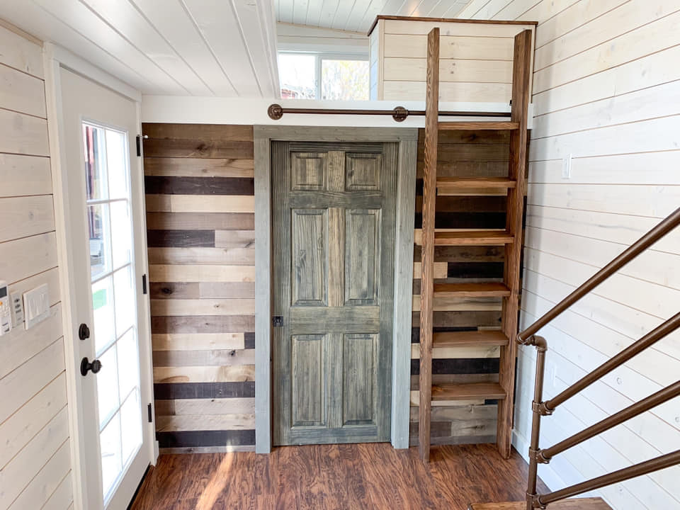 Tiny home interior with storage stairs and sliding barn door