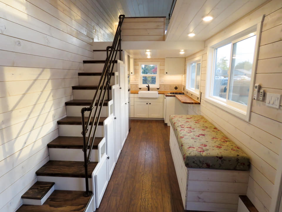 Finished tiny home interior with kitchen, storage stairs and wood flooring